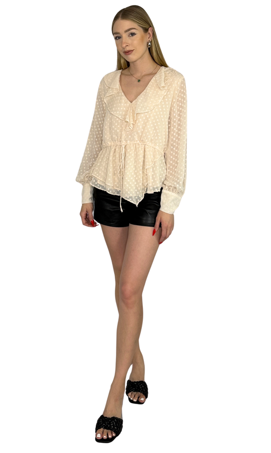 Ivory asymmetrical top featuring an adjustable drawstring waist tie and button tabbed cuffs, designed for a sophisticated look from day to night.