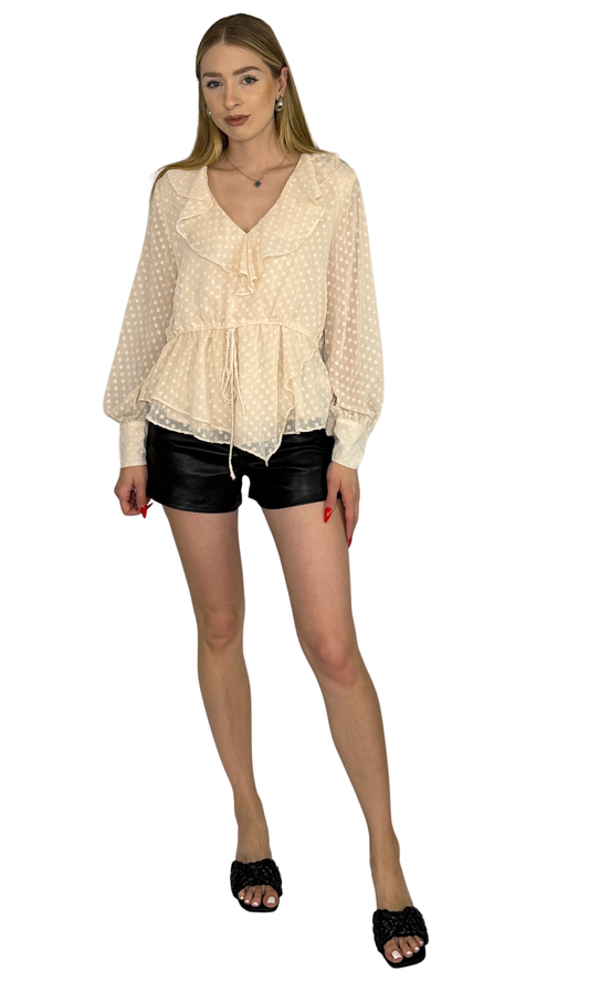 Ivory asymmetrical top featuring an adjustable drawstring waist tie and button tabbed cuffs, designed for a sophisticated look from day to night.