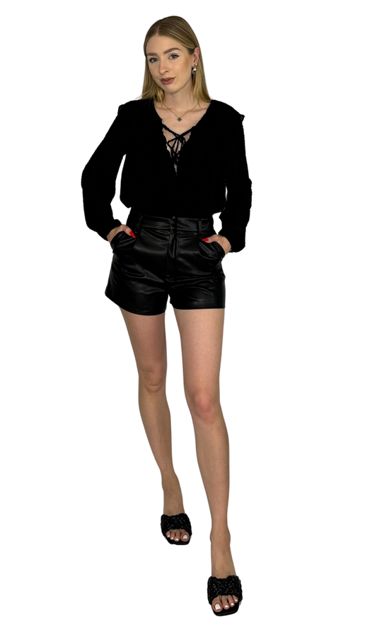 Adjustable Swiss dot blouse with a ruffled lace-up front, elastic sleeves, and a flirty feminine design, available in black and ivory.