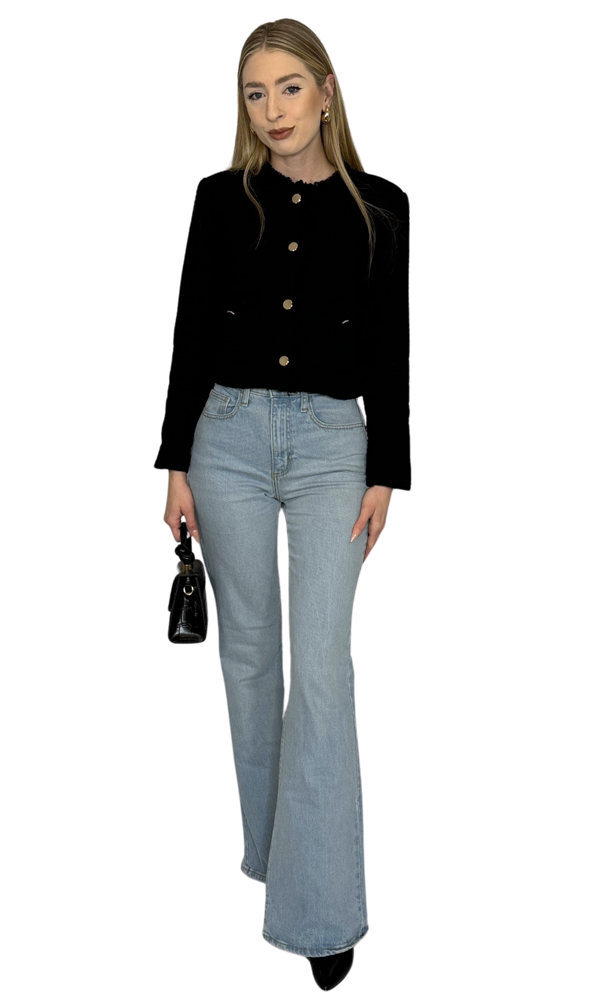 A woman wearing a tweed jacket with a mock neckline, long sleeves, and button-down closure. The jacket is black with gold buttons, and she is also wearing light blue jeans and carrying a black bag.